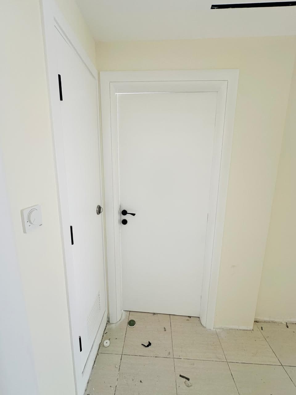 Freshly installed white-painted interior door and frame with a wall-mounted dimmer switch, photographed during final fit-out.