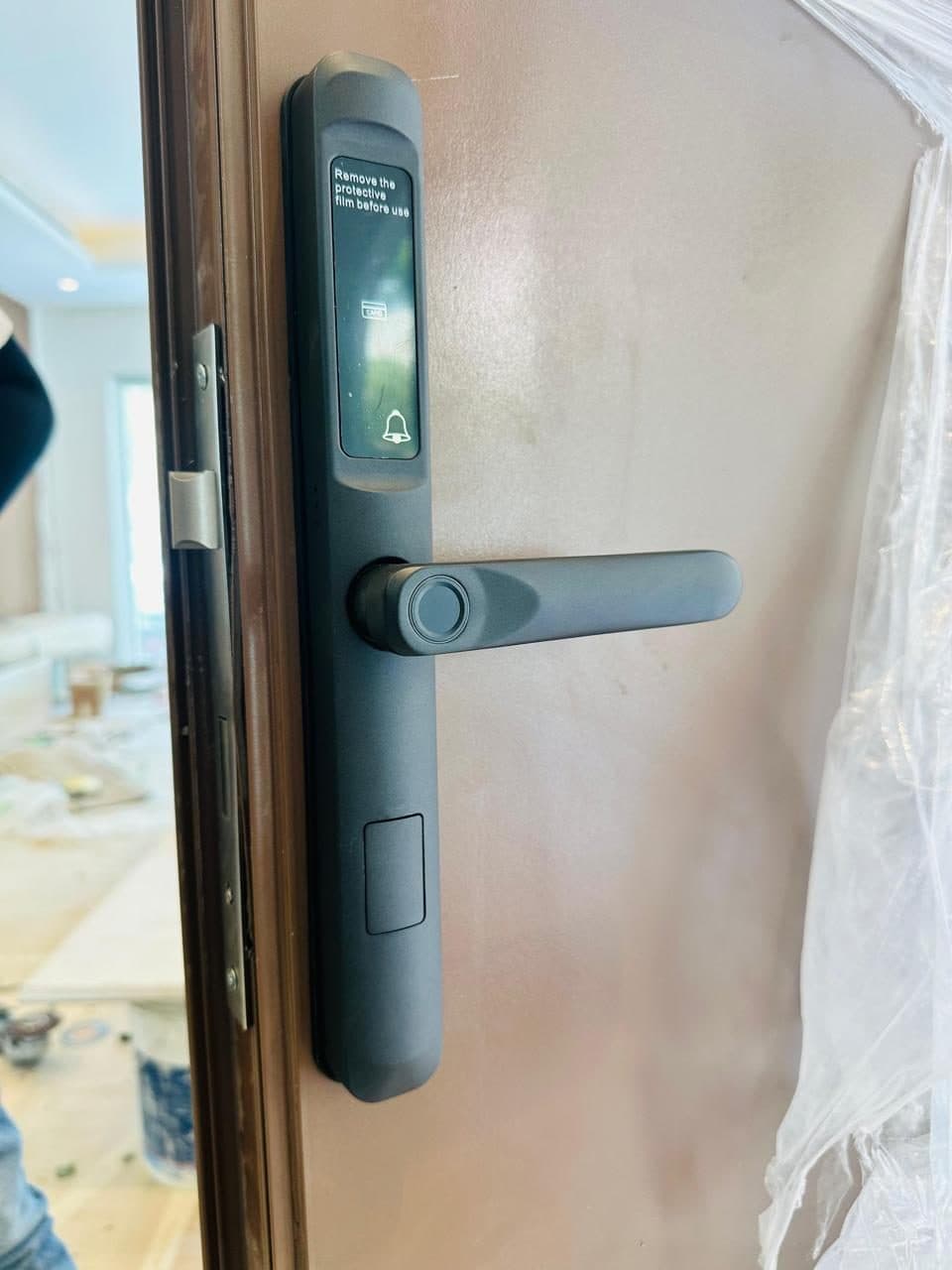 Card and fingerprint smart door lock fitted to an entrance door during a security upgrade, alongside ongoing painting works.