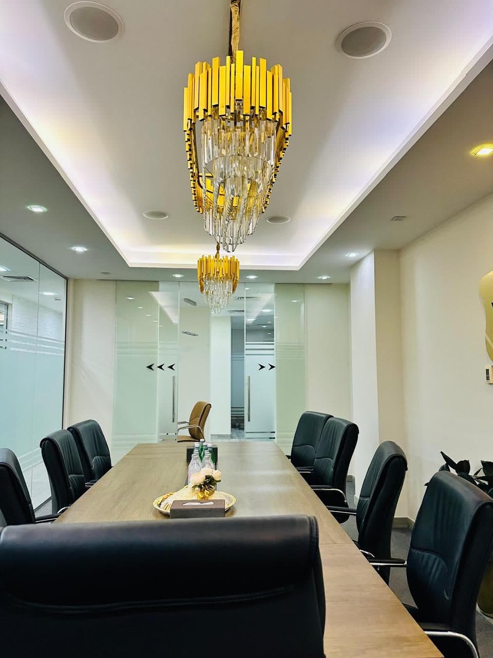 Gypsum cove ceiling with recessed lighting in a boardroom fit-out, finished alongside frosted glass partition doors and statement chandeliers.