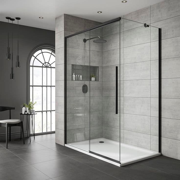 Frameless glass shower enclosure with black hardware against tiled walls